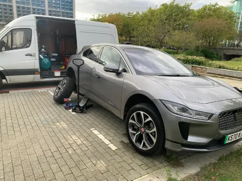 At-work mobile tyre fitting service van servicing a car in an office car park, providing convenient tyre replacement across Beds, Bucks, and Herts.